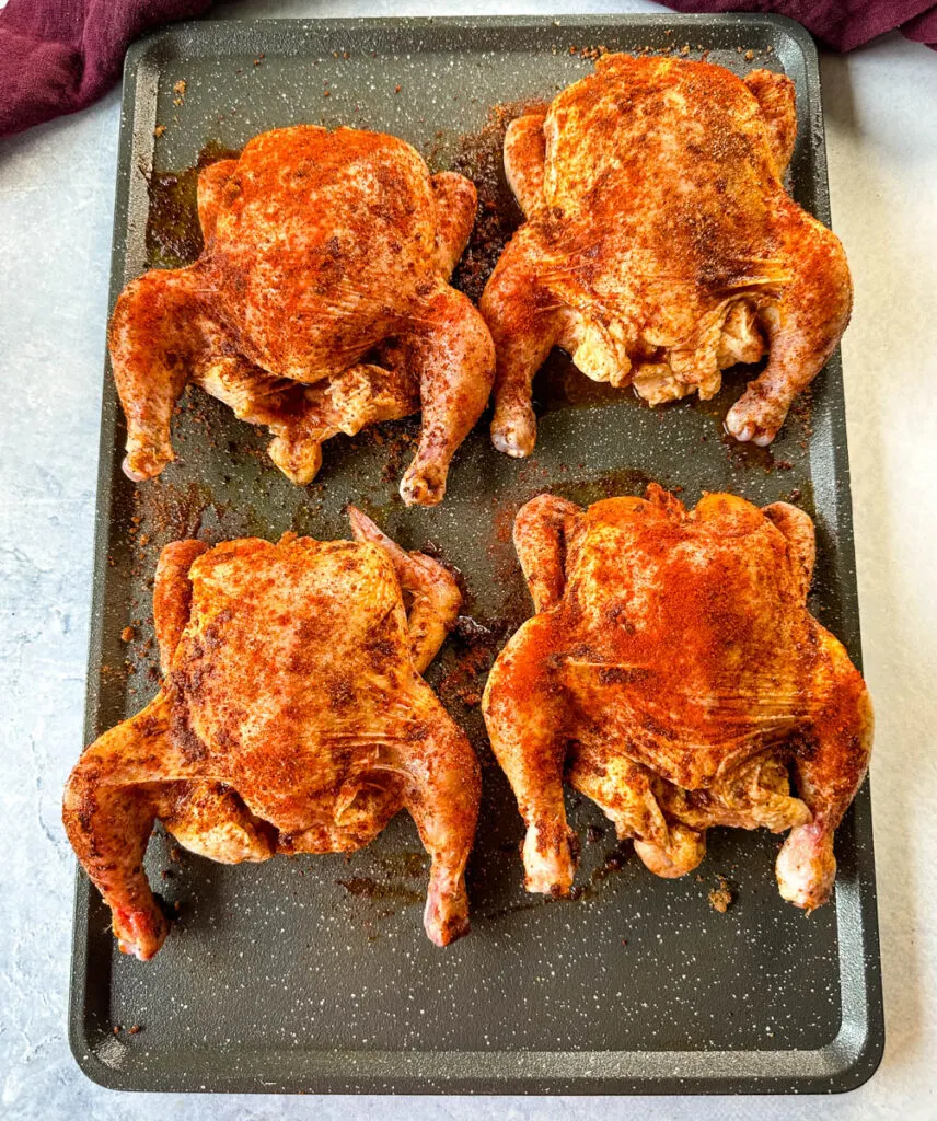 raw seasoned Cornish hens on a sheet pan