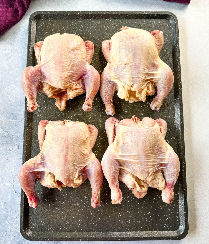 raw Cornish hens on a sheet pan