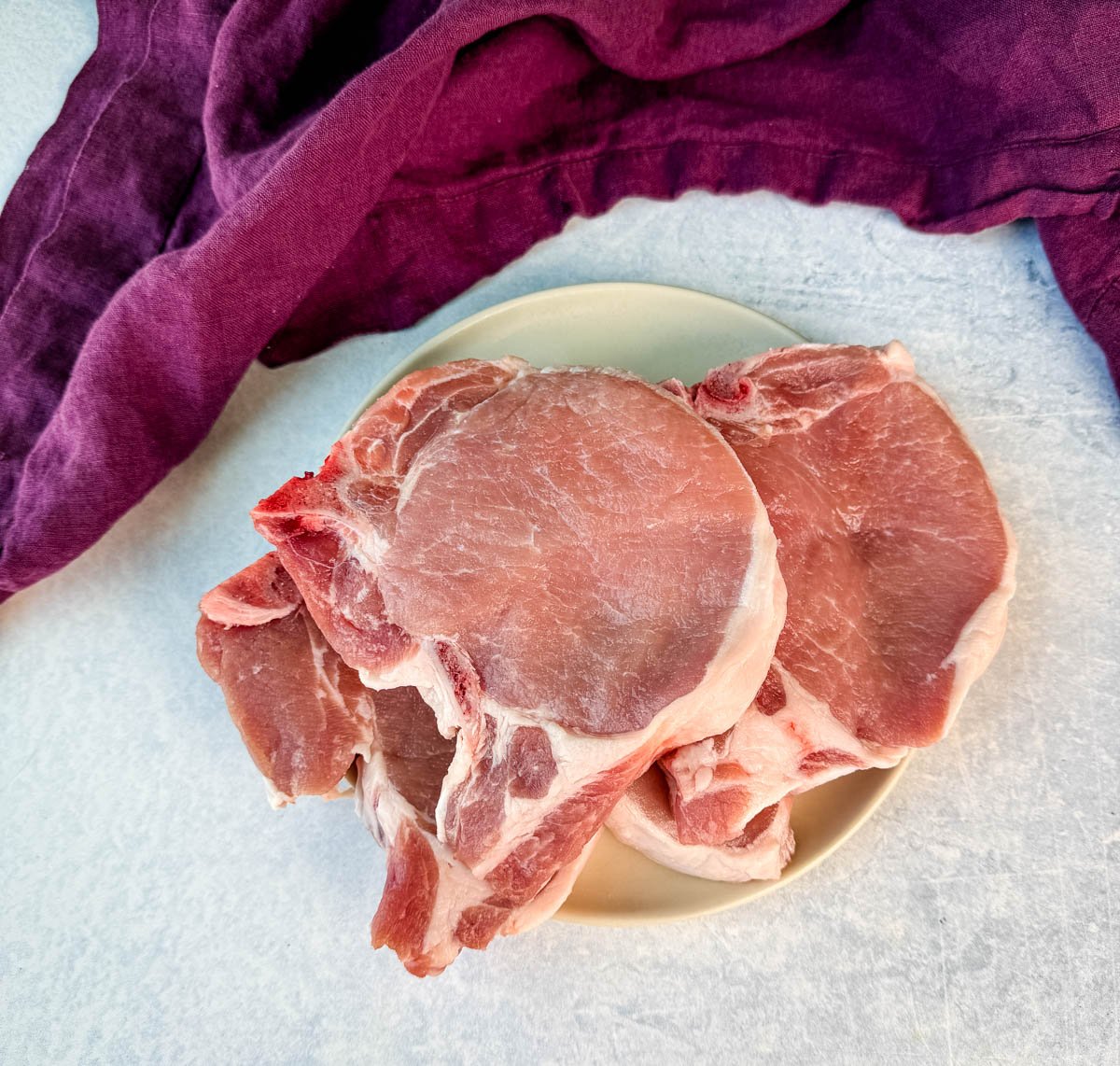 A plate of raw bone-in pork chops.