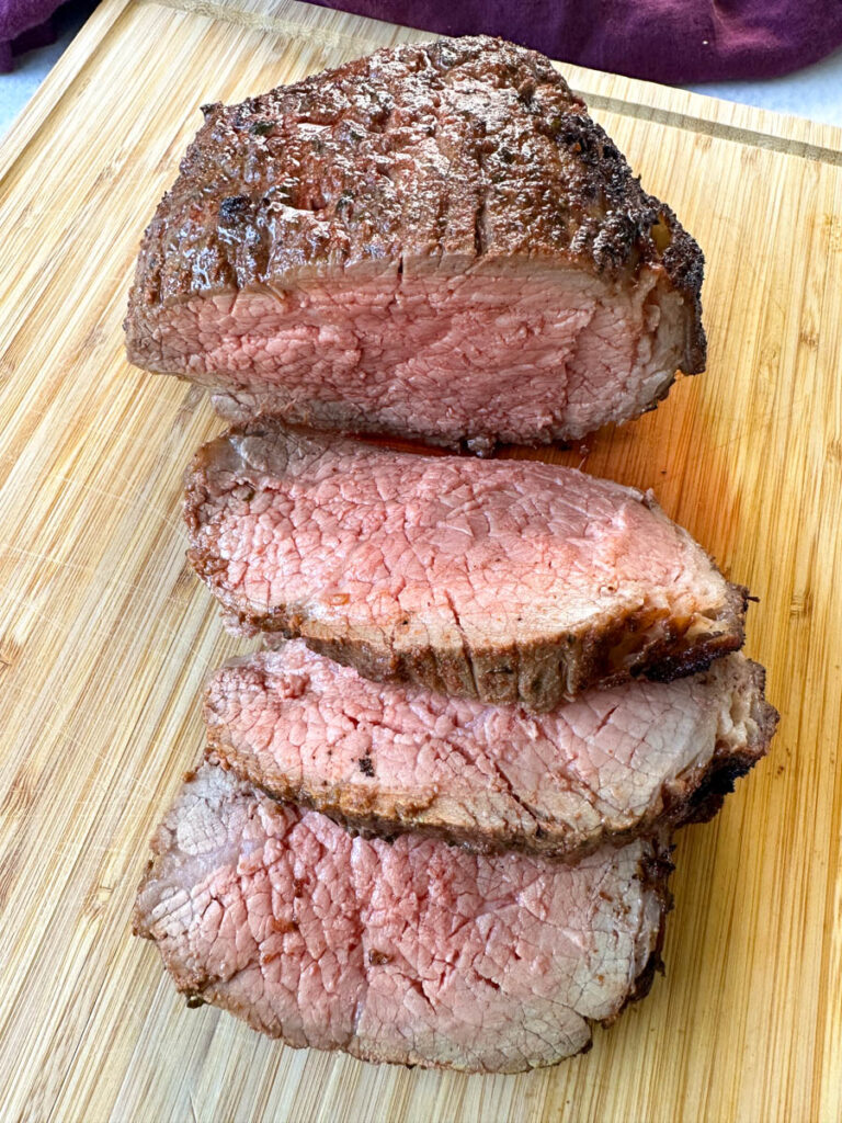 air fryer roast beef sliced on a bamboo cutting board