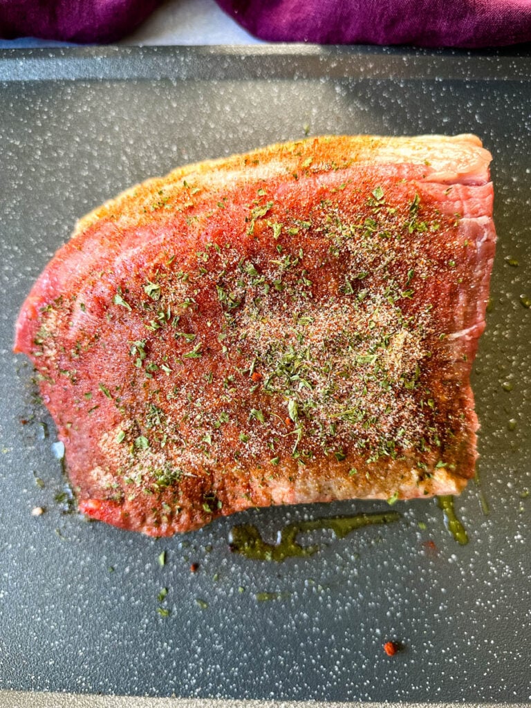 raw seasoned roast beef on a sheet pan