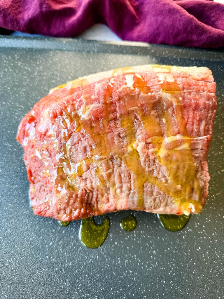 raw roast beef on a sheet pan drizzled with olive oil