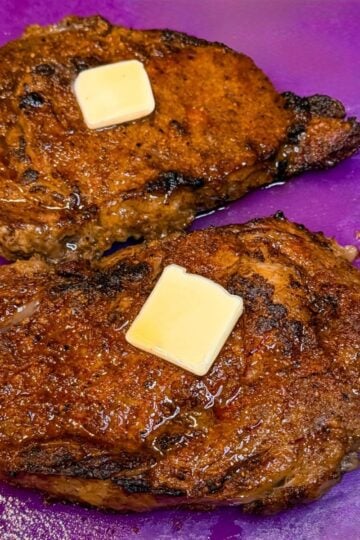 Thick slices of air fryer ribeye steak arranged on a cutting board, showcasing a tender medium-rare interior and golden-brown crust.