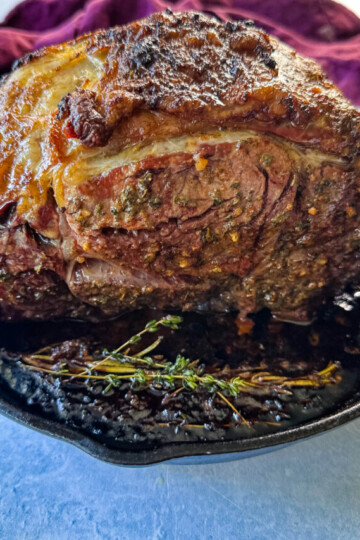roasted garlic herb butter prime rib in a cast iron skillet