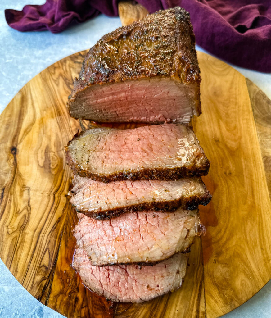 sliced eye of round roast beef on a bamboo board