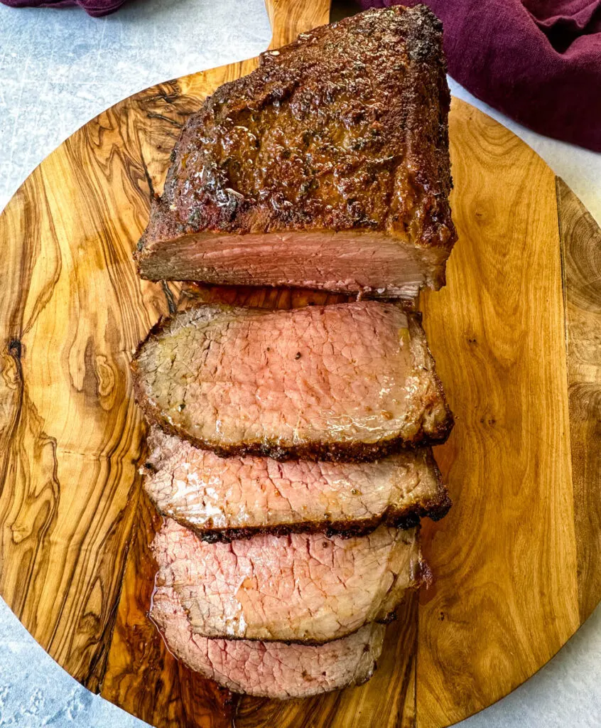 sliced eye of round roast beef on a bamboo board