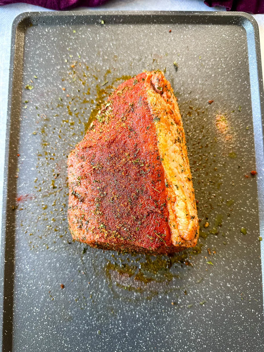 seasoned raw eye of round roast beef on a sheet pan