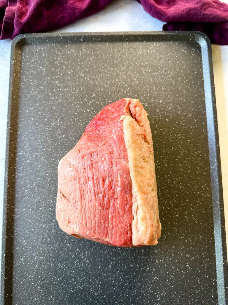 raw eye of round roast beef on a sheet pan