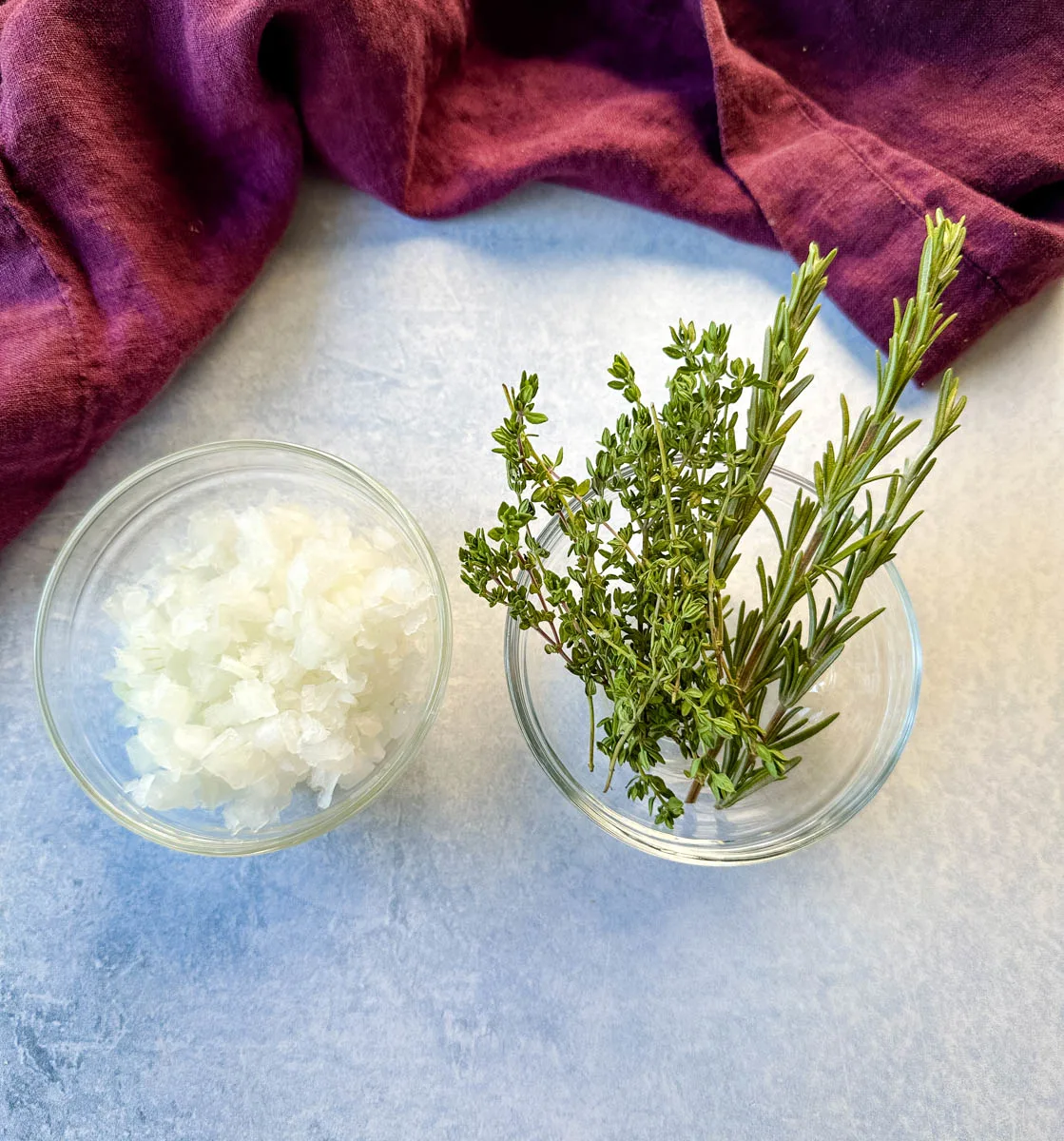 white onions, fresh rosemary, and fresh thyme in separate glass bowls