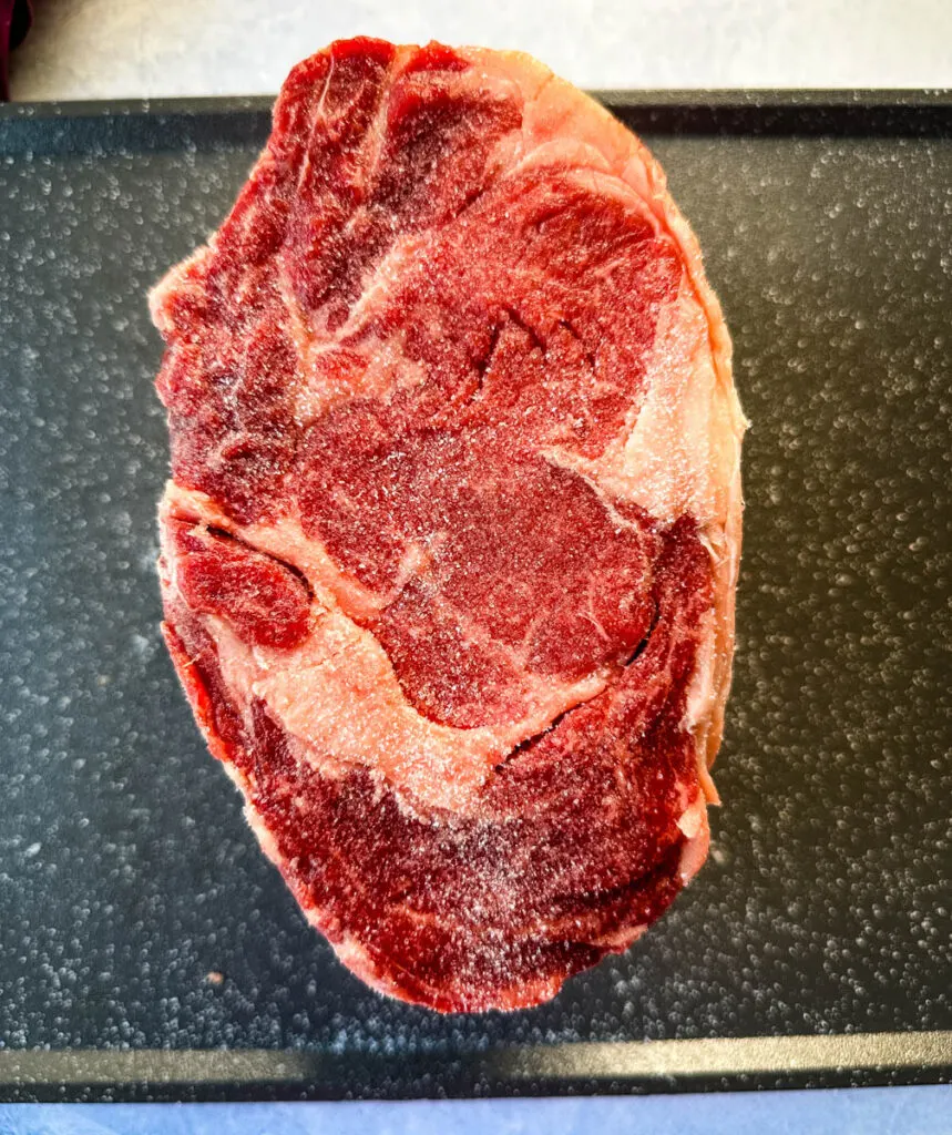 raw prime rib roast on a sheet pan with Kosher salt