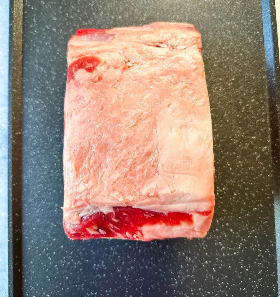 raw prime rib roast on a sheet pan