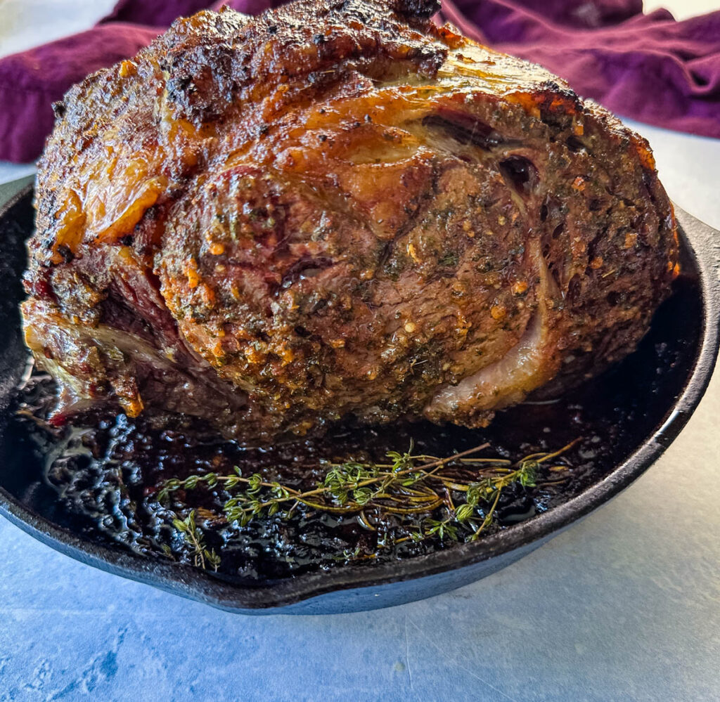 roasted garlic herb butter prime rib in a cast iron skillet