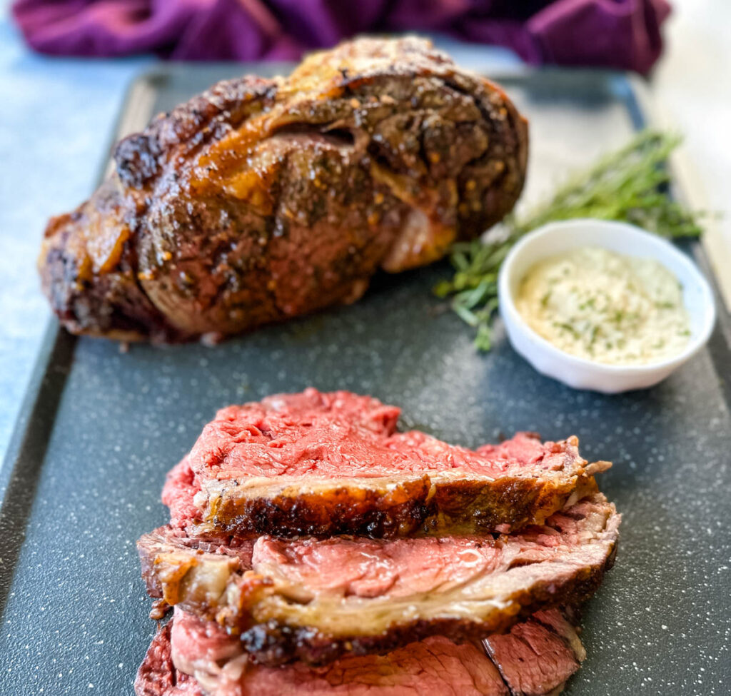 garlic herb butter roasted prime rib sliced on a sheet pan with horseradish