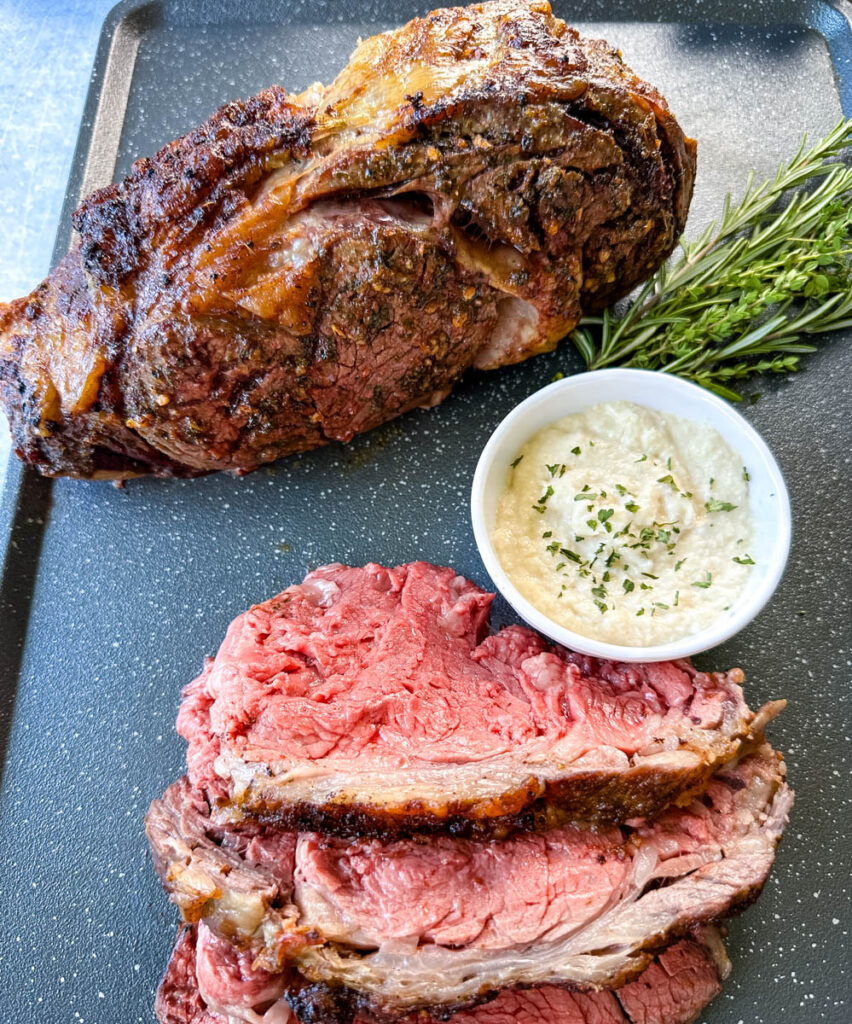 garlic herb butter roasted prime rib sliced on a sheet pan with horseradish