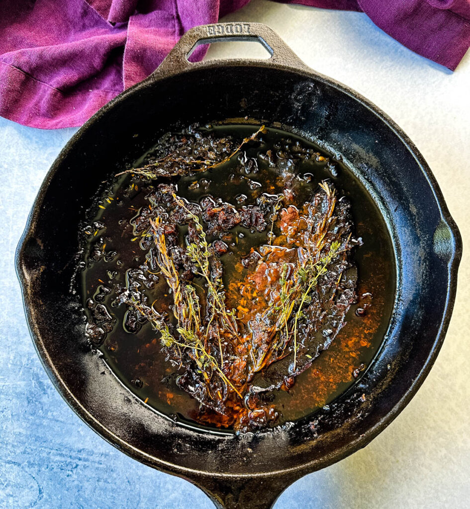 prime rib drippings and herbs in a cast iron skillet