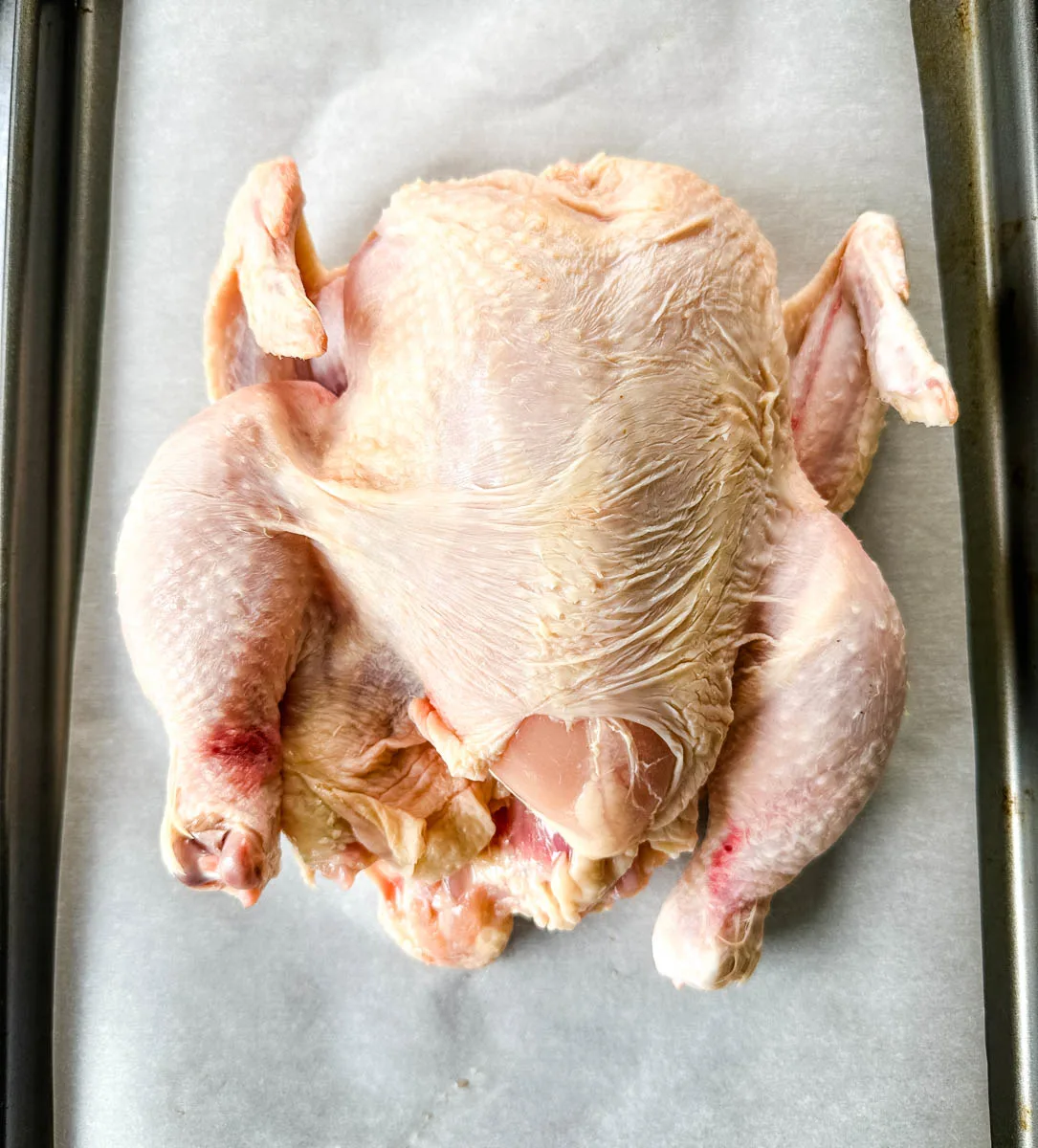 raw whole chicken on parchment paper