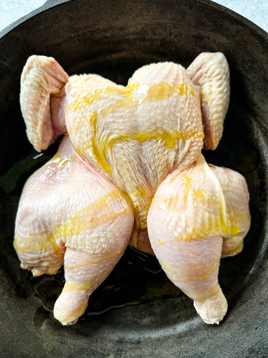 raw Thanksgiving chicken in a cast iron skillet drizzled with olive oil