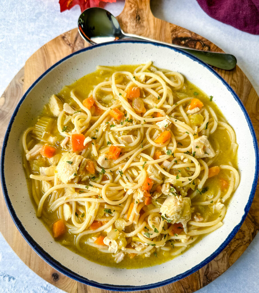 rotisserie chicken noodle soup with carrots and celery in a white bowl