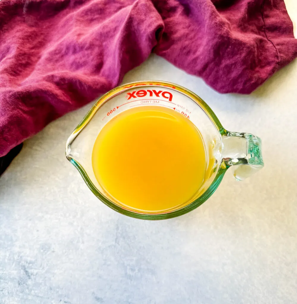 chicken broth in a glass measuring cup