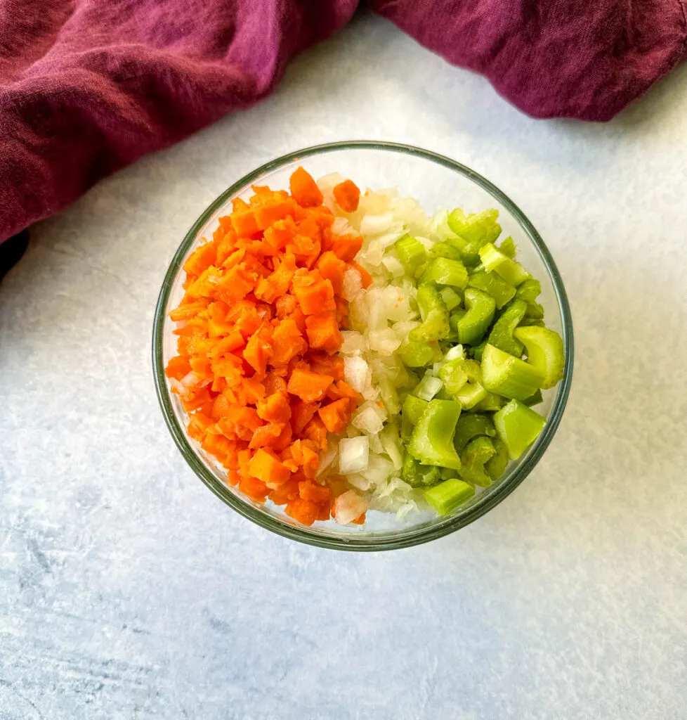 diced carrots, celery, and white onions in a glass bowl