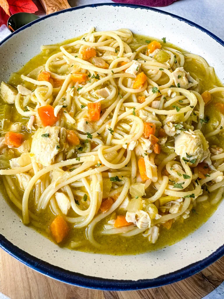 rotisserie chicken noodle soup with carrots and celery in a white bowl