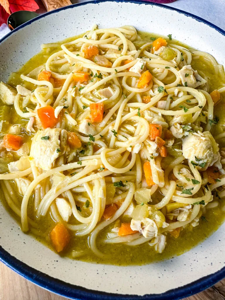 rotisserie chicken noodle soup with carrots and celery in a white bowl