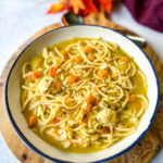 rotisserie chicken noodle soup with carrots and celery in a white bowl