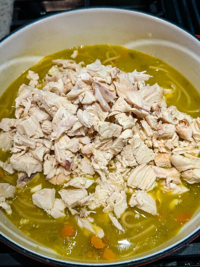 rotisserie chicken noodle soup with carrots and celery in a Dutch oven