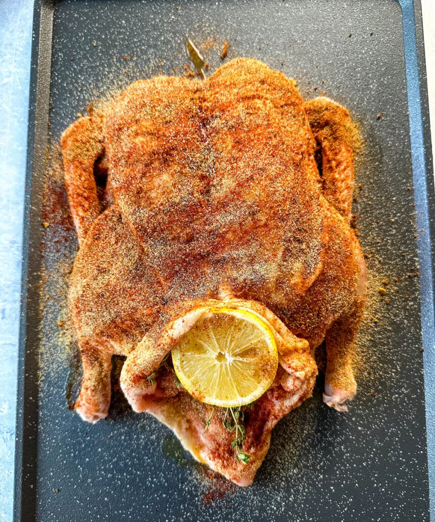 raw seasoned whole duck on a sheet pan stuffed with lemon and herbs