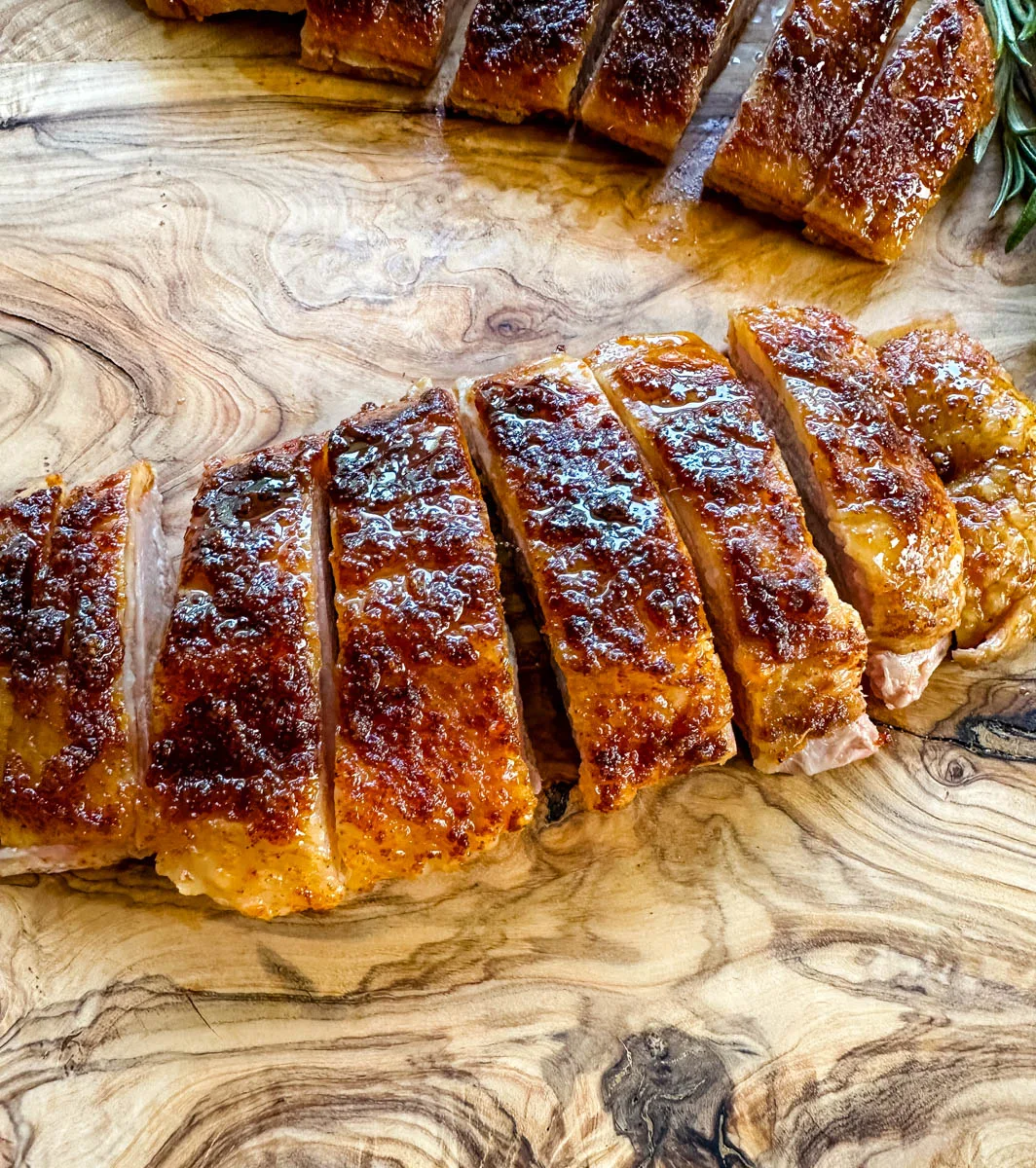 smoked duck breast sliced on a wooden cutting board
