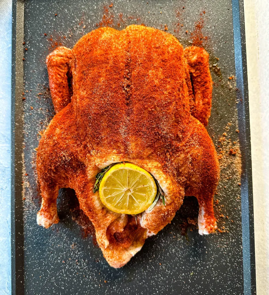 raw seasoned whole duck on a sheet pan stuffed with lemon and herbs