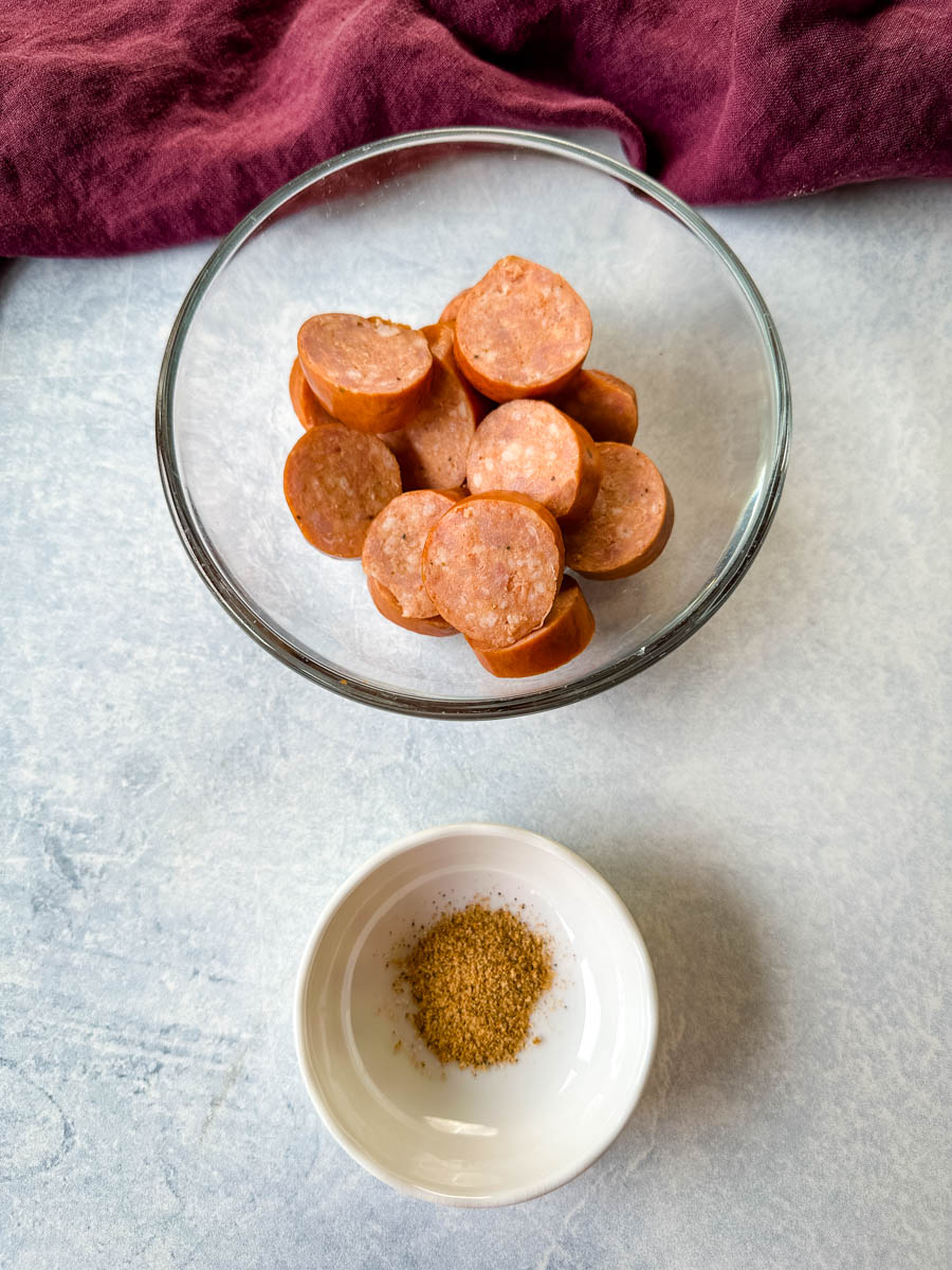 sliced andouille sausage and Creole seasoning in separate bowls