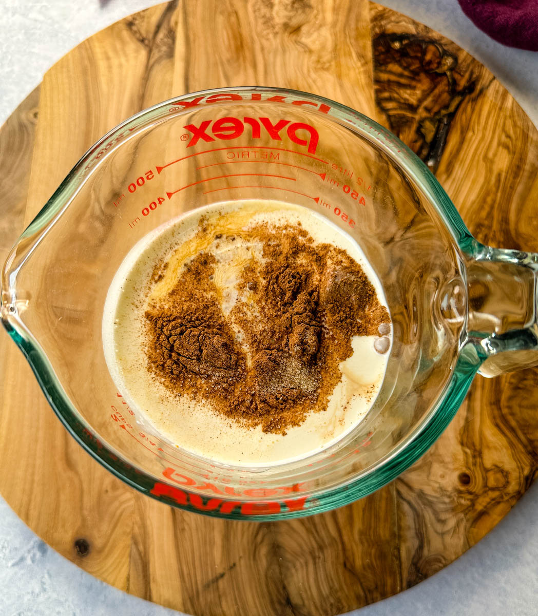 heavy cream with pumpkin and pumpkin pie spice in a glass measuring cup