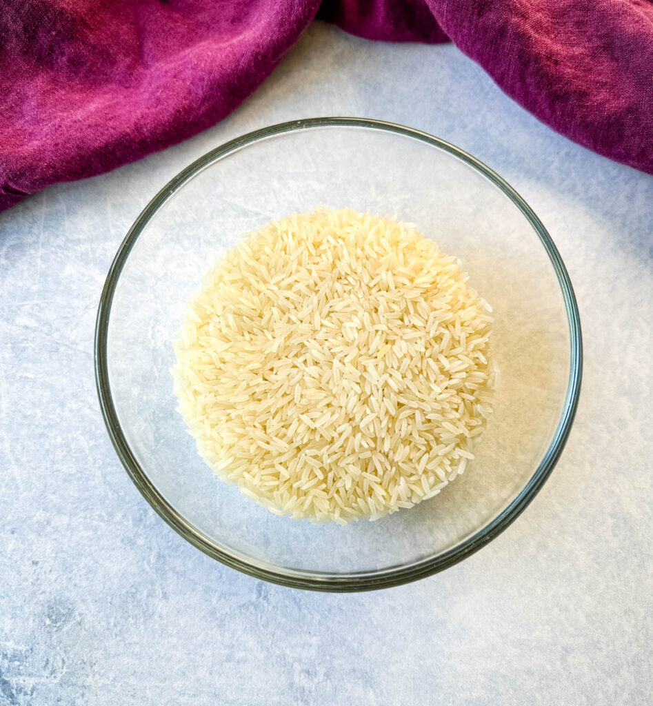 dry, uncooked long grain white rice in a glass bowl