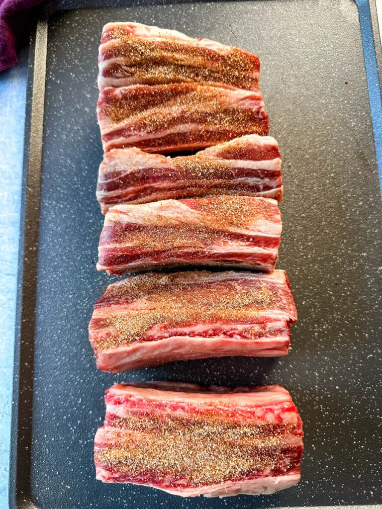 raw short ribs seasoned with spices on a sheet pan