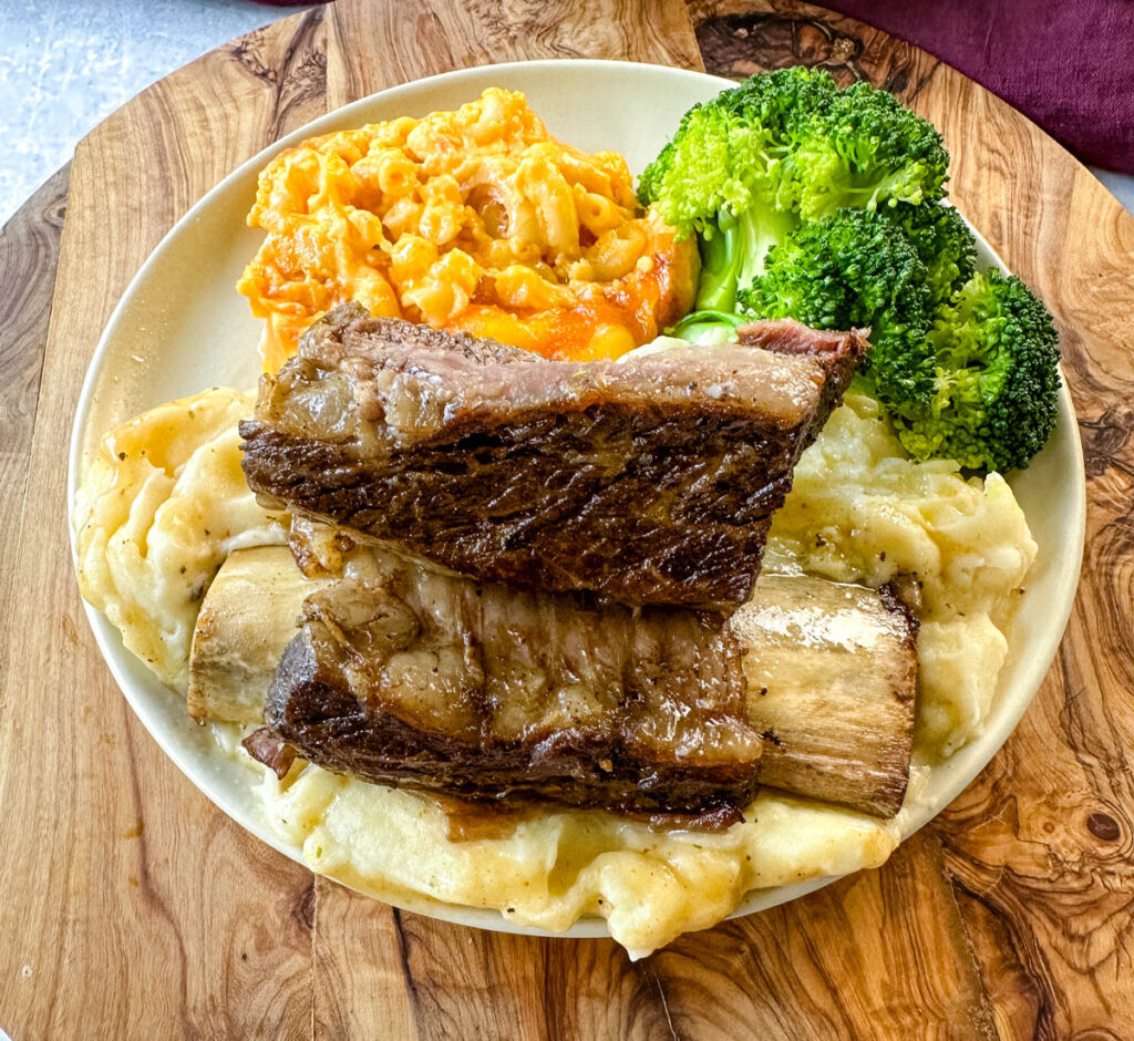 braised beef short ribs with mashed potatoes, mac and cheese, and broccoli on a plate