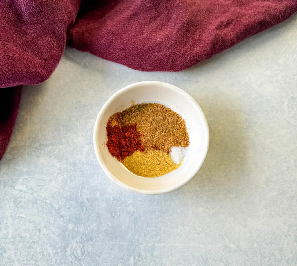Creole seasoning, garlic powder, and smoked paprika in a white bowl
