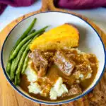 beef tips and gravy with green beans and cornbread in a bowl