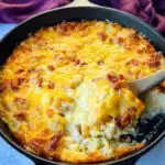 hashbrown casserole with bacon and cheese in a cast iron skillet