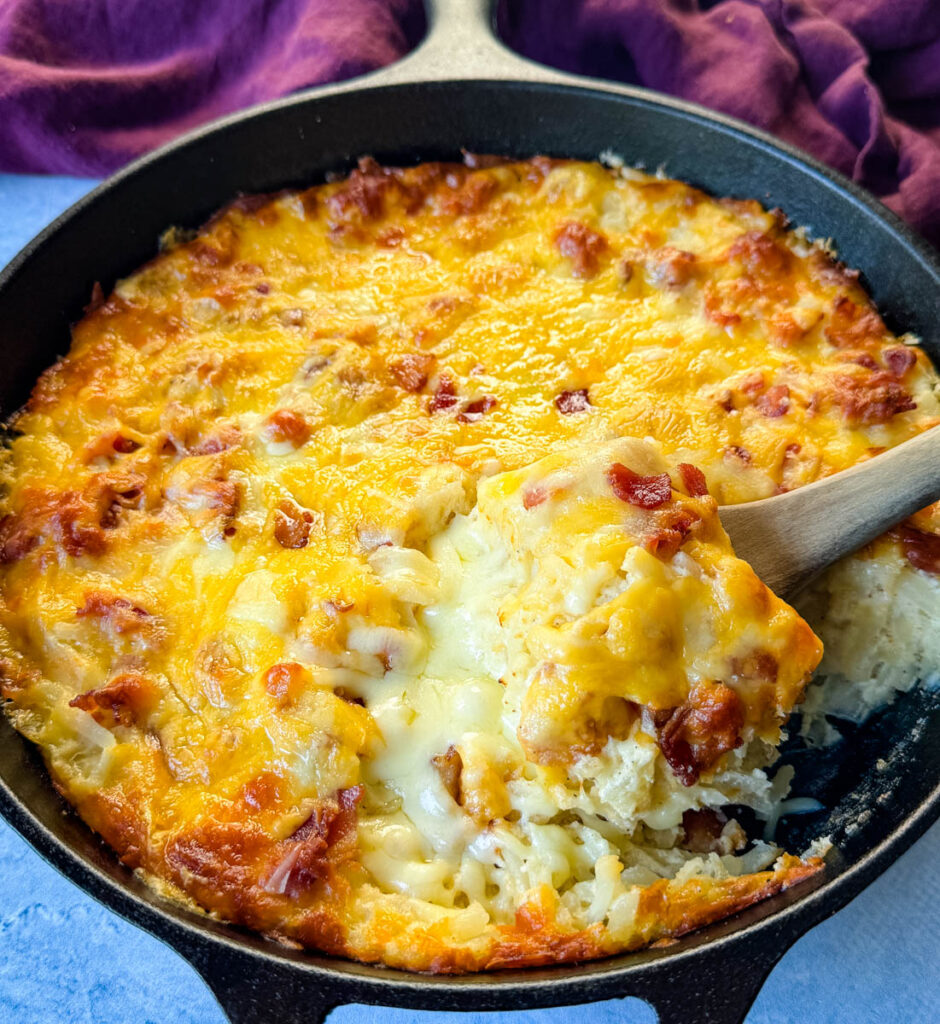 hashbrown casserole with bacon and cheese in a cast iron skillet