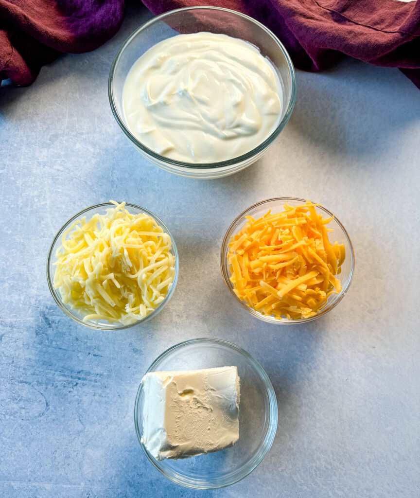 sour cream, grated mozzarella, grated cheddar, and cream cheese in separate glass bowls