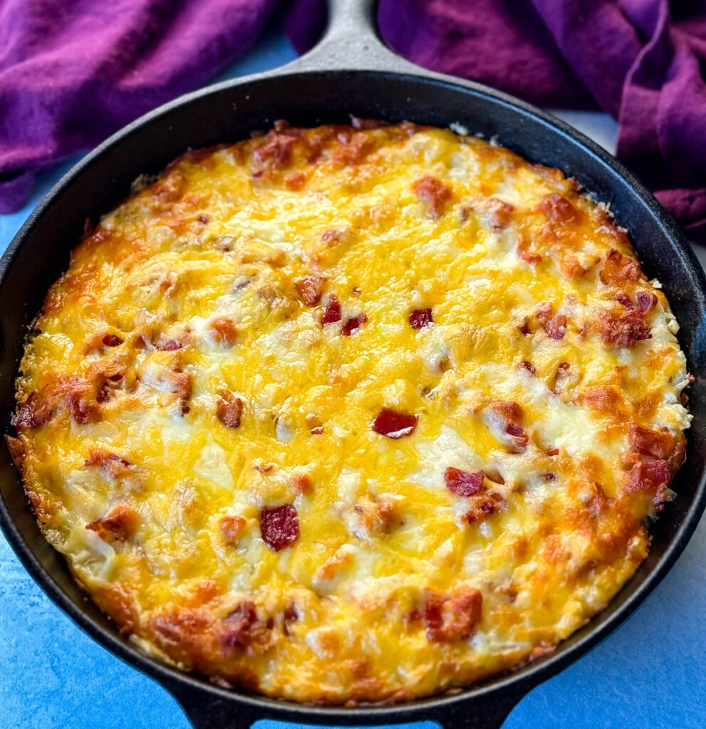 hashbrown casserole with bacon and cheese in a cast iron skillet