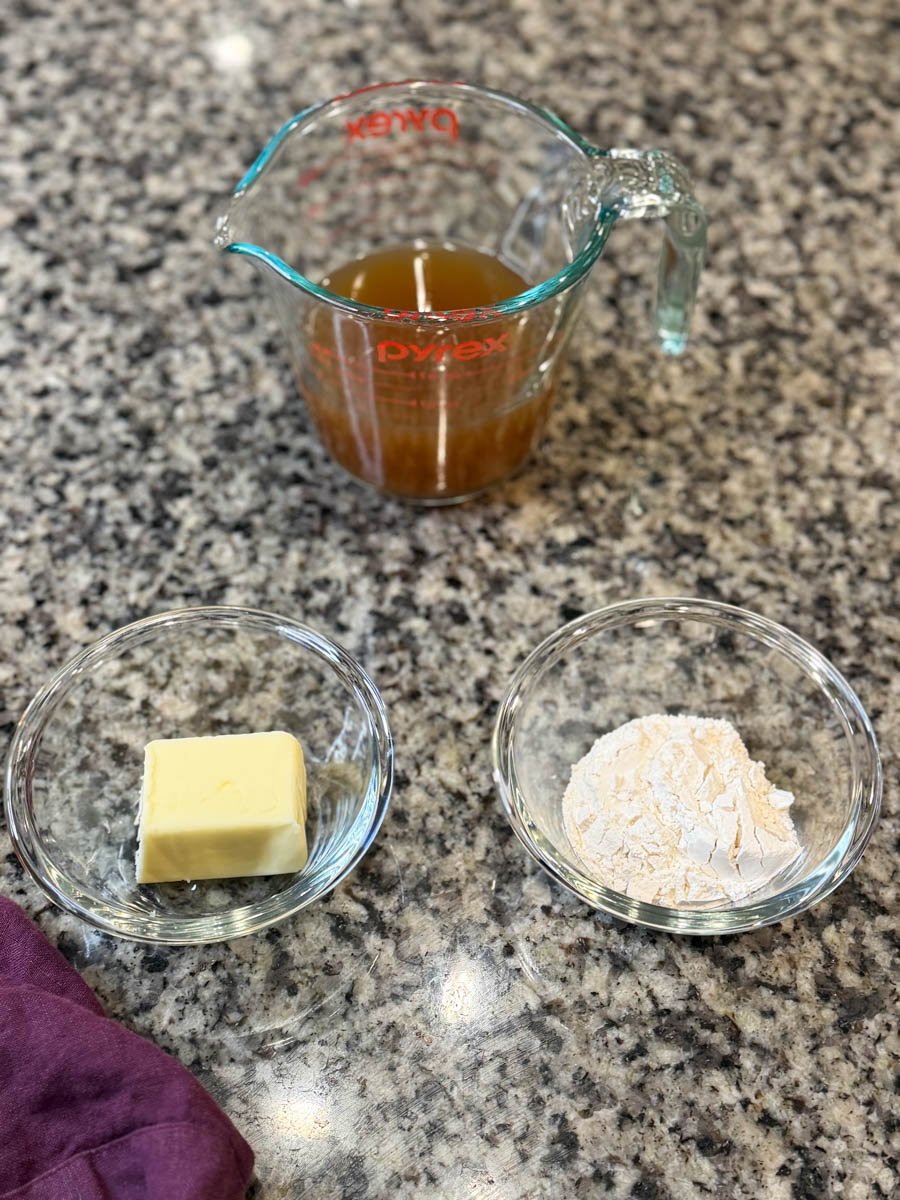 Measured broth, butter, and flour on a countertop, showing the ingredients used to make the smothered chicken gravy.