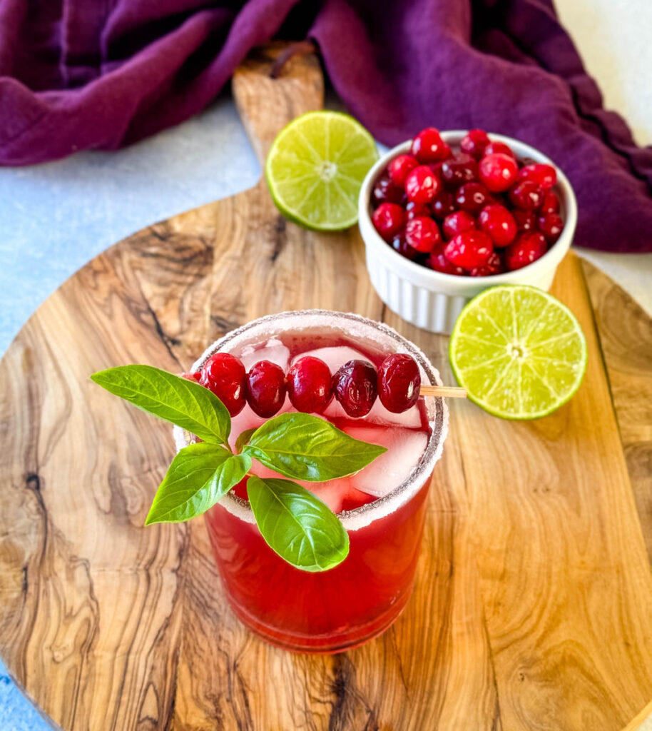 cranberry margarita with fresh cranberries and herbs in a glass