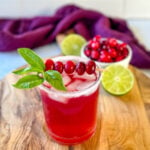 cranberry margarita with fresh cranberries and herbs in a glass