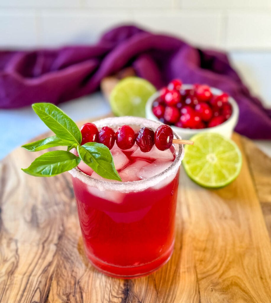 cranberry margarita with fresh cranberries and herbs in a glass