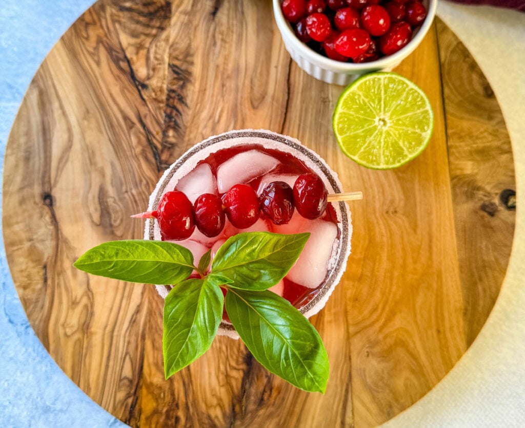 cranberry margarita with fresh cranberries and herbs in a glass