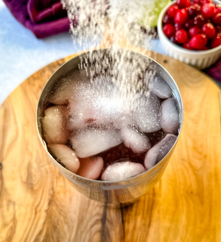 cranberry margarita in a cocktail shaker with sweetener