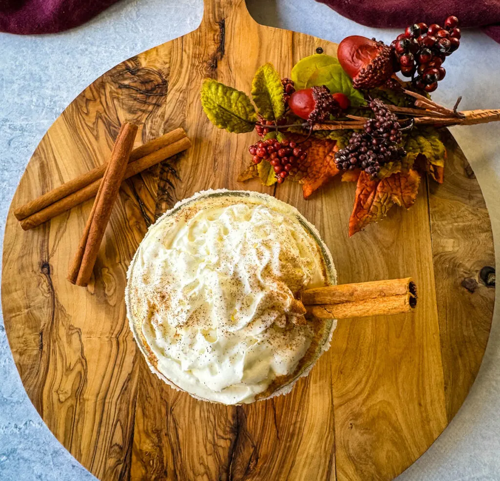 spiked eggnog with liquor, cinnamon, and whipped cream on a flat surface