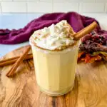 spiked eggnog with liquor, cinnamon, and whipped cream on a flat surface